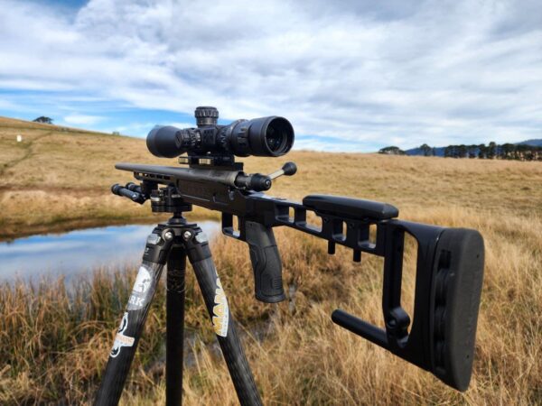 Precision Australian-made rifle shooting gear with scope on a tripod in outdoor landscape.